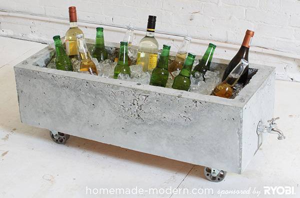 A long concrete wheeled container with a spigot on the end contains ice and bottles of alcohol.