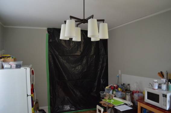 A black tarp is thrown over a doorway in a kitchen.