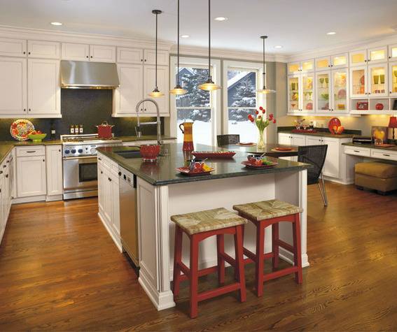 A large kitchen has an island, stools, a small dining table, and a lot of cabinets.