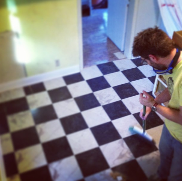 A man sweeps a dirty checkerboard floor.