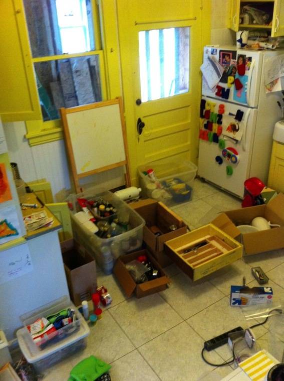 A kitchen floor is covered with items in boxes.