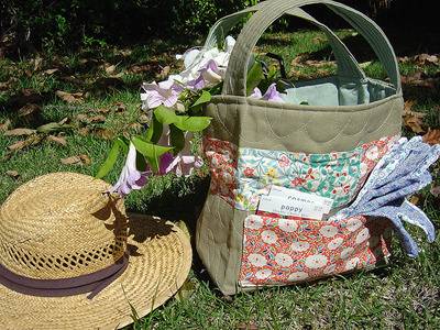 A straw hat and a cloth handbag sitting on the grass outside.