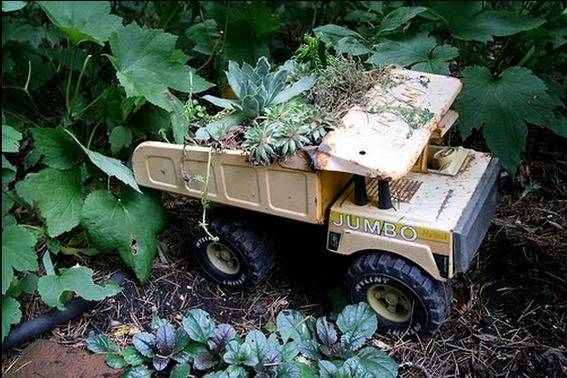 A small metal dump truck that has been used as a flower planter.