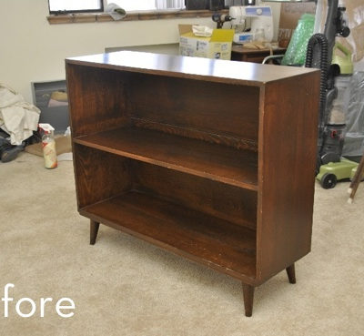 A brown wooden shelf sits in a messy room.