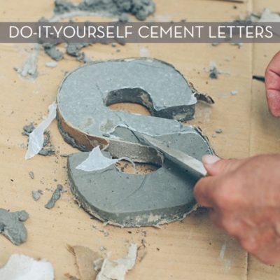 A letter S being carved out of cement.
