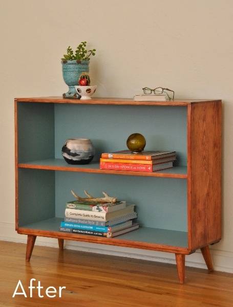 A wooden and blue shelf has books and decoration on it.
