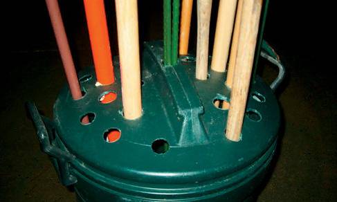 Holes cut into the lid of a garbage can to store brooms, mops, etc.