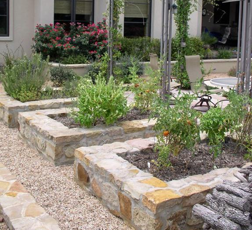 Plants grow in dirt in stone planters outside.