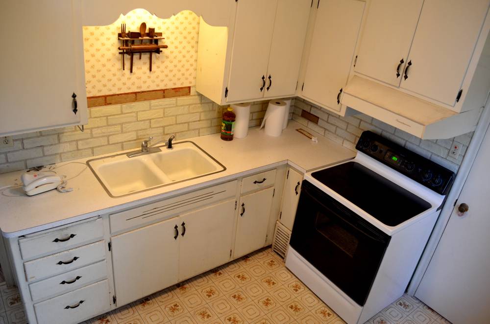 A kitchen with white cupboards and drawers.