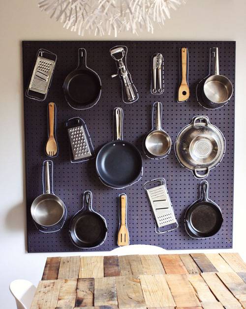 Graters, pans, skillets, and spatulas all mounted on the wall.