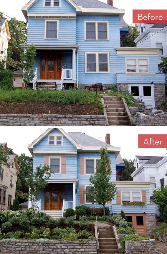 A blue two story house with green bushes in front.