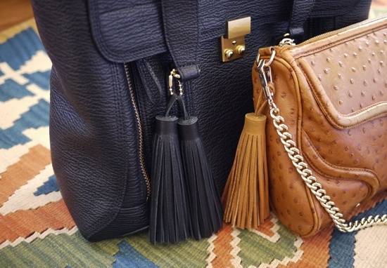 A black and a brown purse on a multi colored rug.