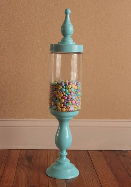 A light blue ornate glass stand filled halfway with colored candies.