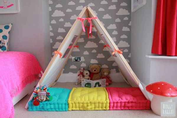 A kid's bedroom has a small open fort with cushions.