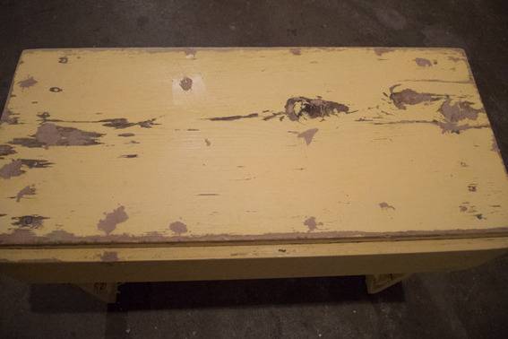An old table has flaking yellow paint on it.