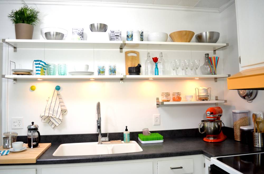 A white sink is in a black counter with a white wall.