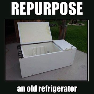 Refrigerator on its side on the ground with door open.