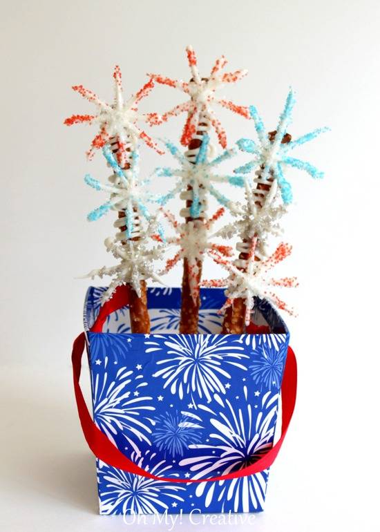 A blue and white fireworks bag with a red stap conatins three craft sticks with spiky branches on them.