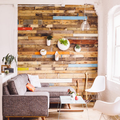 A sitting room that has a shiplap wall and a bright open window.