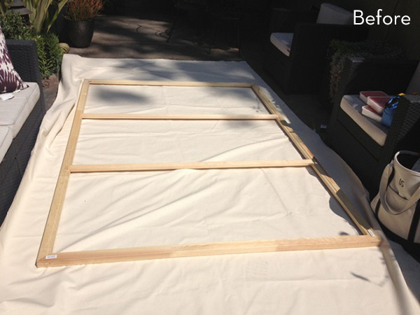 A huge white sheet laid out on the ground with a wooden frame with three sections on it.
