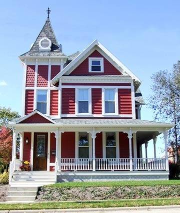 A red burgundy colonial home has white trimmings.