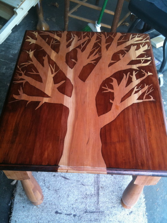 Inlaid wood panel decorated with a tree with table legs.