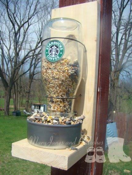 A large Starbucks bottle has been turned upside down to make a bird feeder.