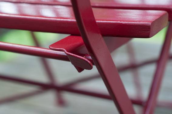 A red metal and wood chair has a locking mechanism.