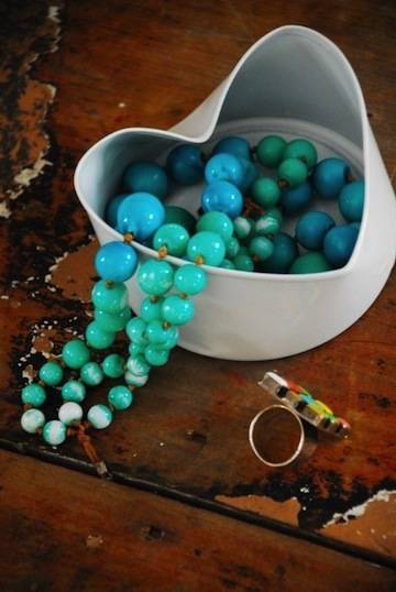 Blue beads sit in a white container on a brown table.