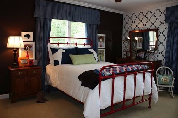A bed with a red frame sits in a room with blue curtains.