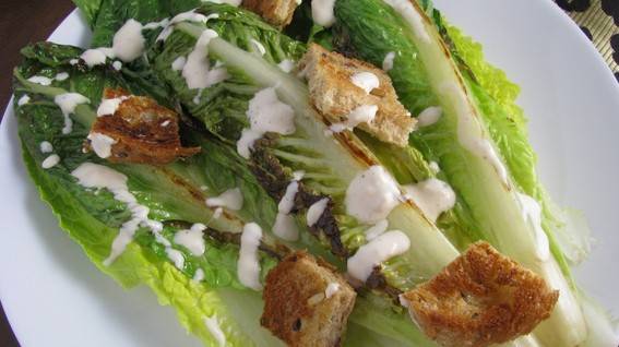 Large lettuce leaves have croutons and dressing on them