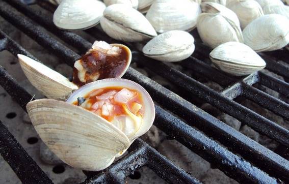 Seashells have been filled with food and are on a grill.