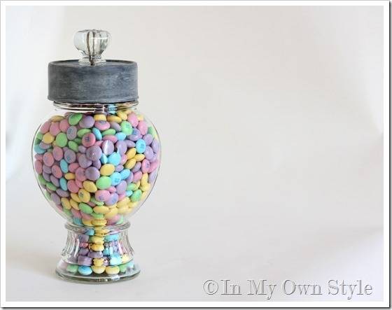 A glass jar full of candy with an elaborate lid.