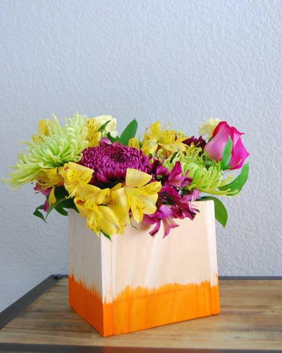 A pink bag with an orange bottom is filed with a boquet of flowers.