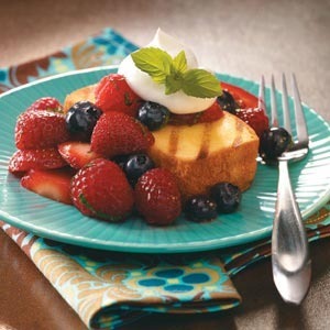 Angel food cake with berries and whip cream on a plate with a fork.