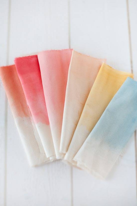 Six colored napkins folded and laying on a white surface.