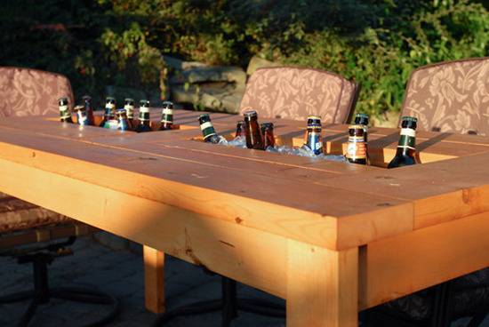 Bottles of beer sit in a cooling area in a table.
