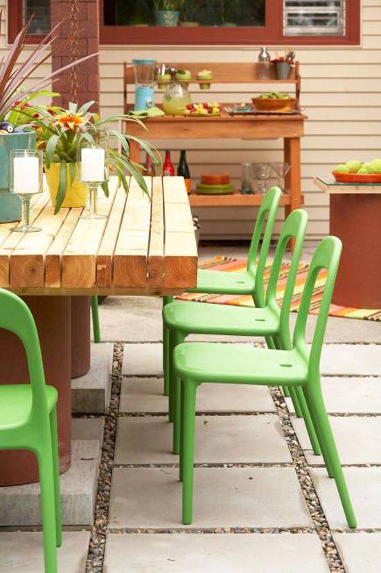 Green chairs surround a wooden table on a patio outside.