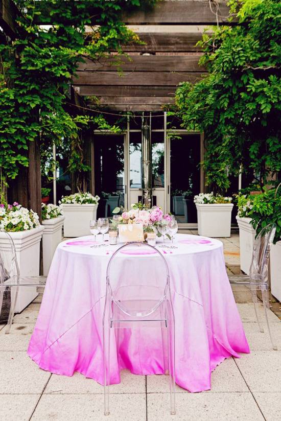 An outdoor patio has a pink table with trees next to it.