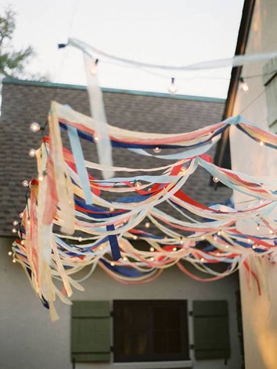 Several colorful ribbons hang from chords next to a roof.