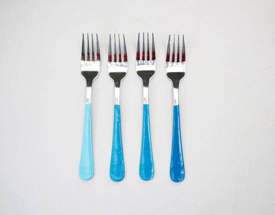 Four silverware forks have three different blue shades.