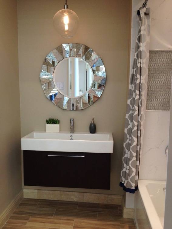 A bathroom with a round mirror and a sink attached to the wall.