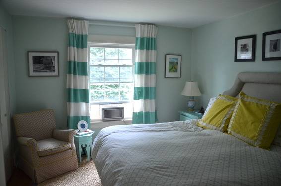 Teal walls with a window that has striped teal and white curtains in a bedroom