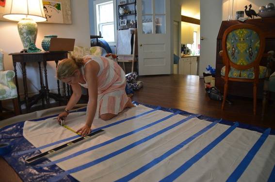 A woman is marketing on a tarp with a tape measurer.