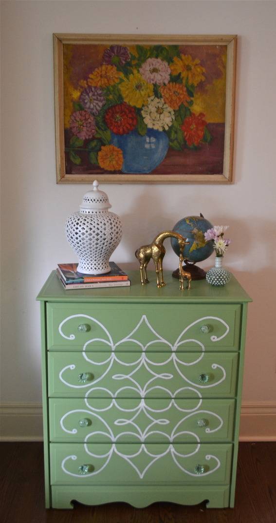 Painting of flowers above a dresser with a painted design.