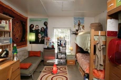 Bunk bed with unmade beds next to posters and couch inside a dorm room.