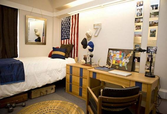 A room that has a wood table and dresser, along with a bed and an American flag