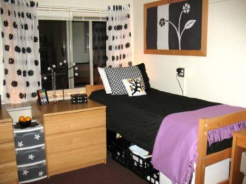 A bedroom with a black and pink bed, and a open window.
