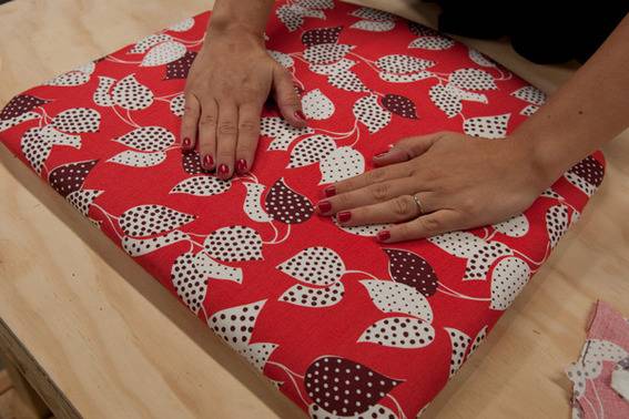 A person places both their hands on a red decorated pillow.