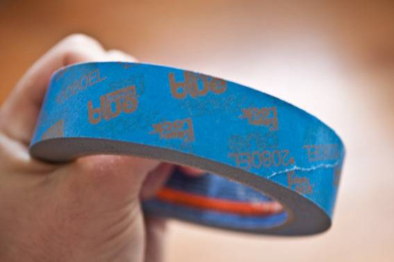 A roll of blue tape being held in someone's hand.